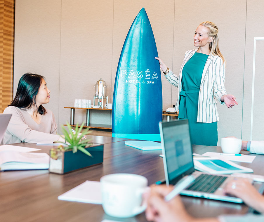 Woman addressing a board meeting holding a surfboard