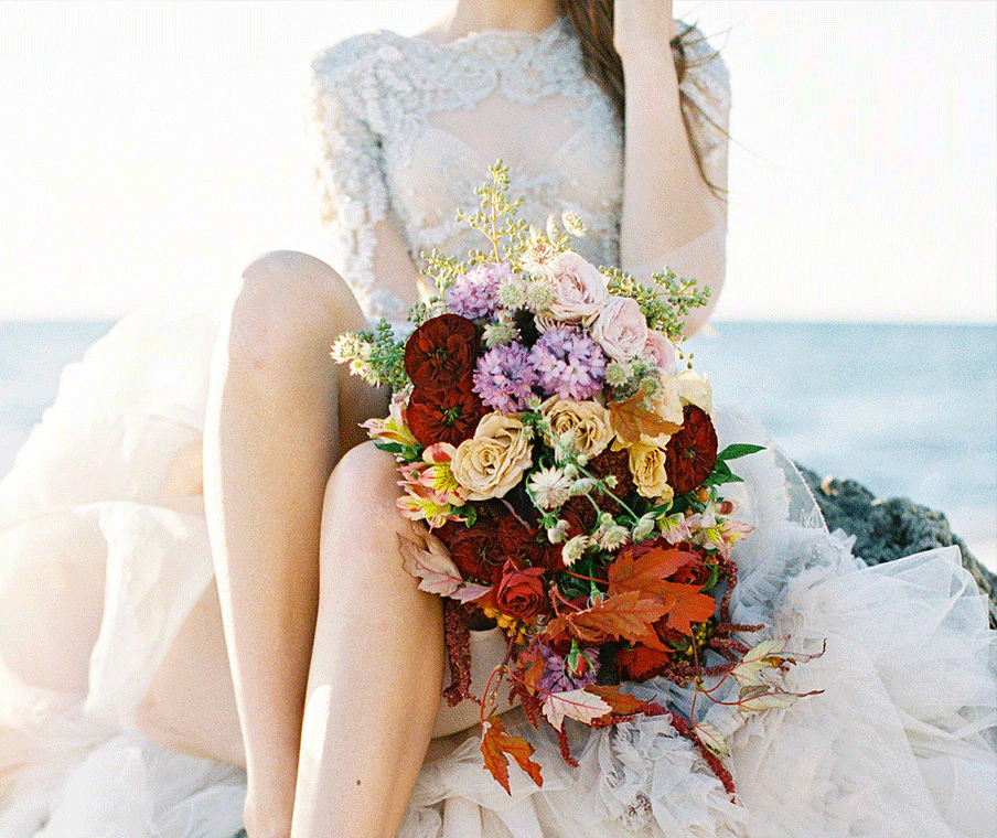 bride holding bouquet near ocean